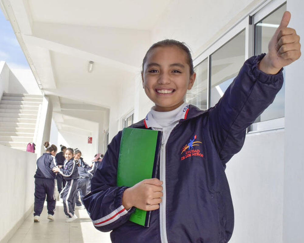 Alumna de Ciudad de los Niños de Monterrey con su cuaderno en la escuela